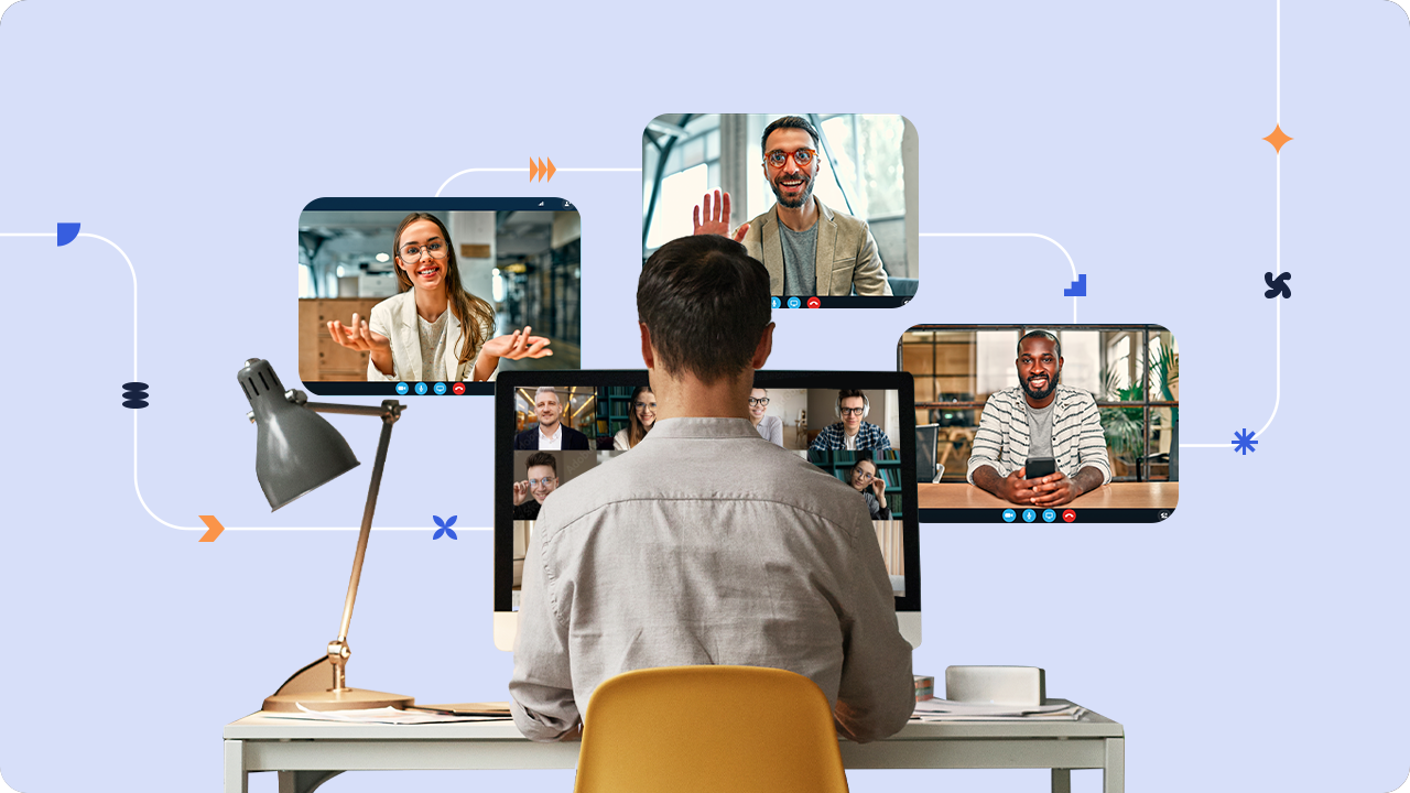 A man sits at a desk meeting with three people on three computer monitors